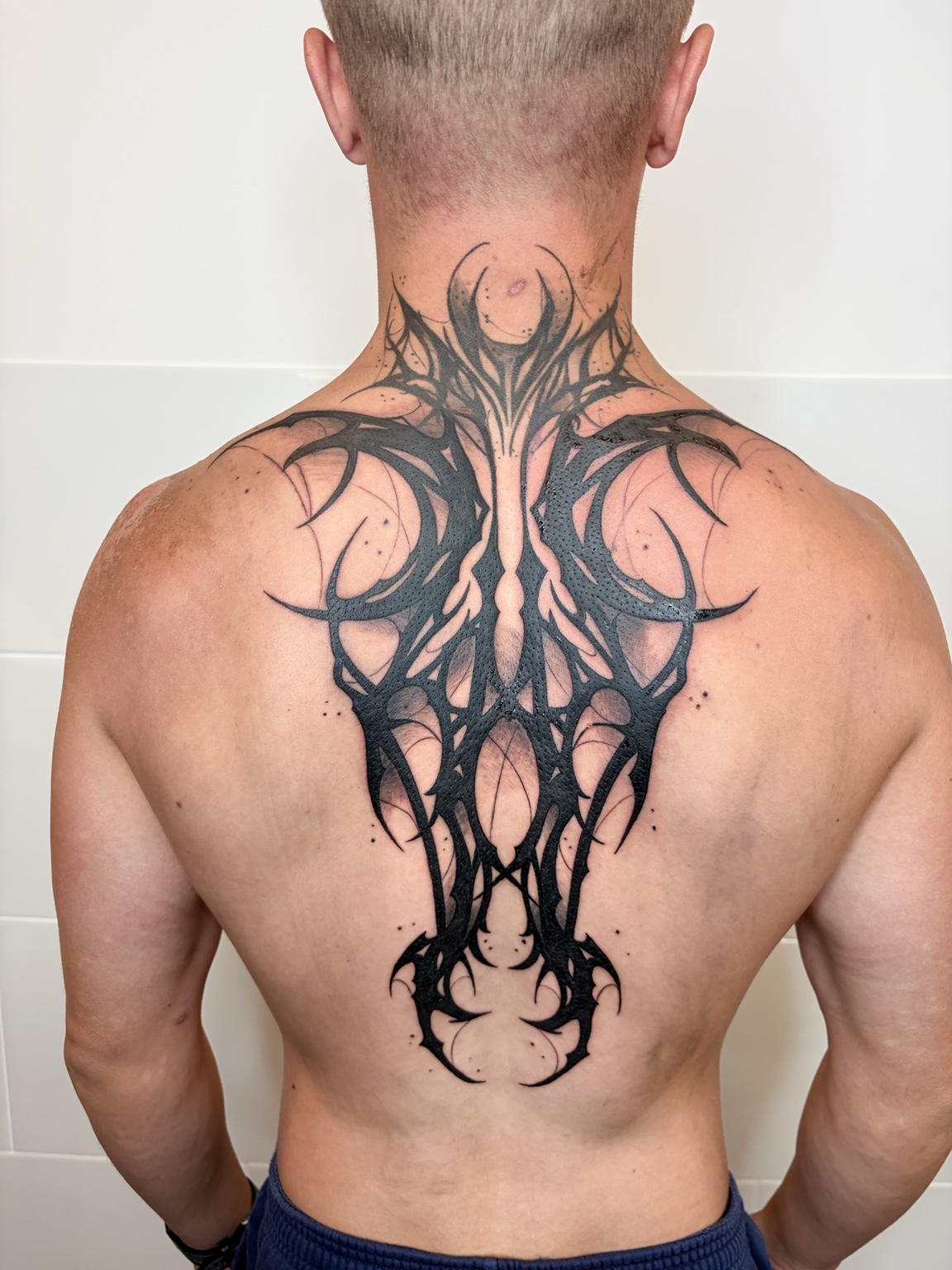 Symmetrisches schwarzes Tribal auf Rücken und Nacken